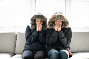 couple-sitting-on-couch-looking-cold