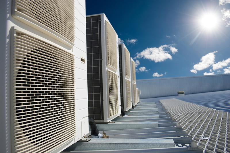 Rows of rooftop HVAC units with a sunny background on a rooftop.