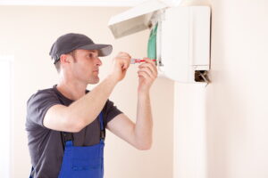Technician performing mini split heat pump installation on a beige wall.